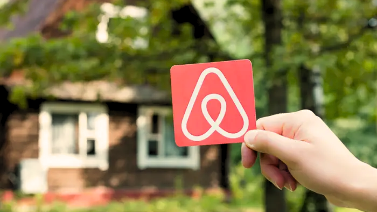 holding airbnb logo with house background